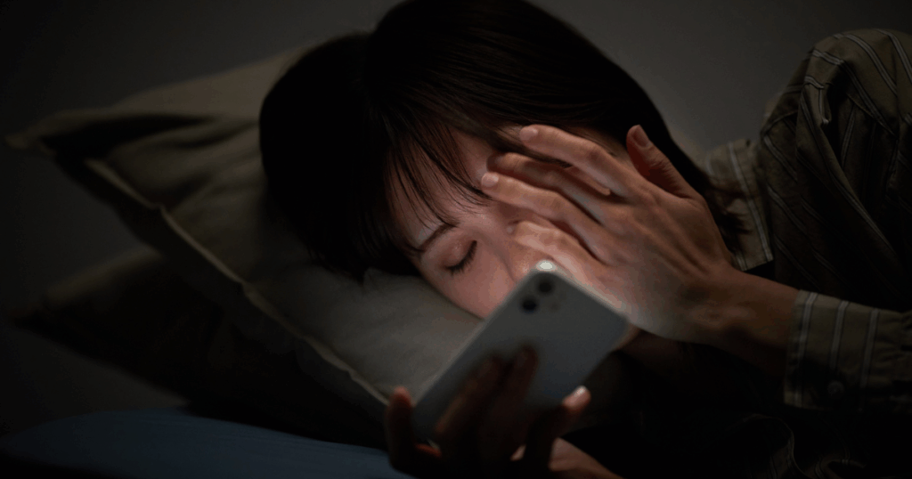 女性が暗闇でスマホを操作する写真